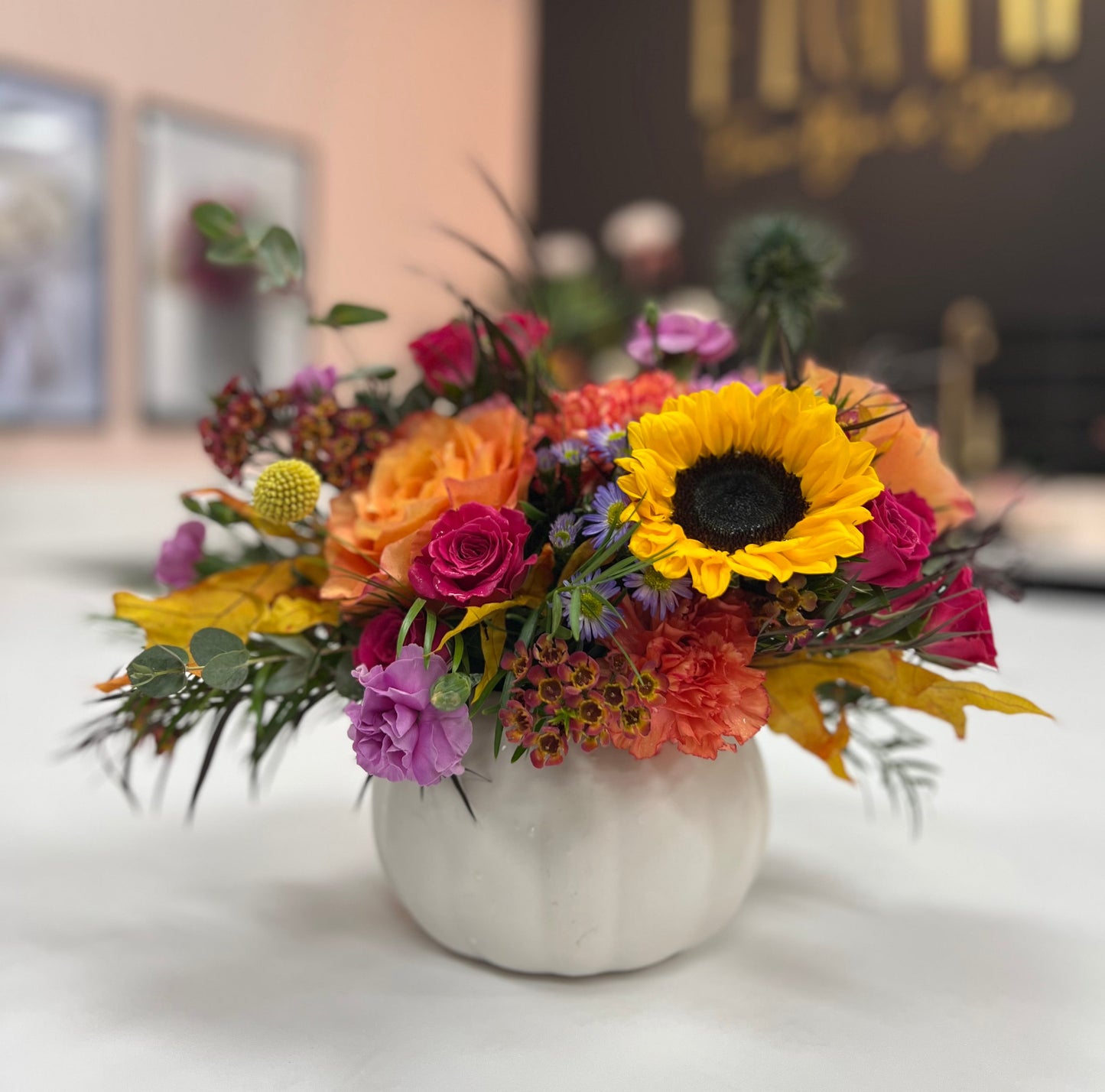 Colorful flower arrangement in a white vase on a table with a blurred background