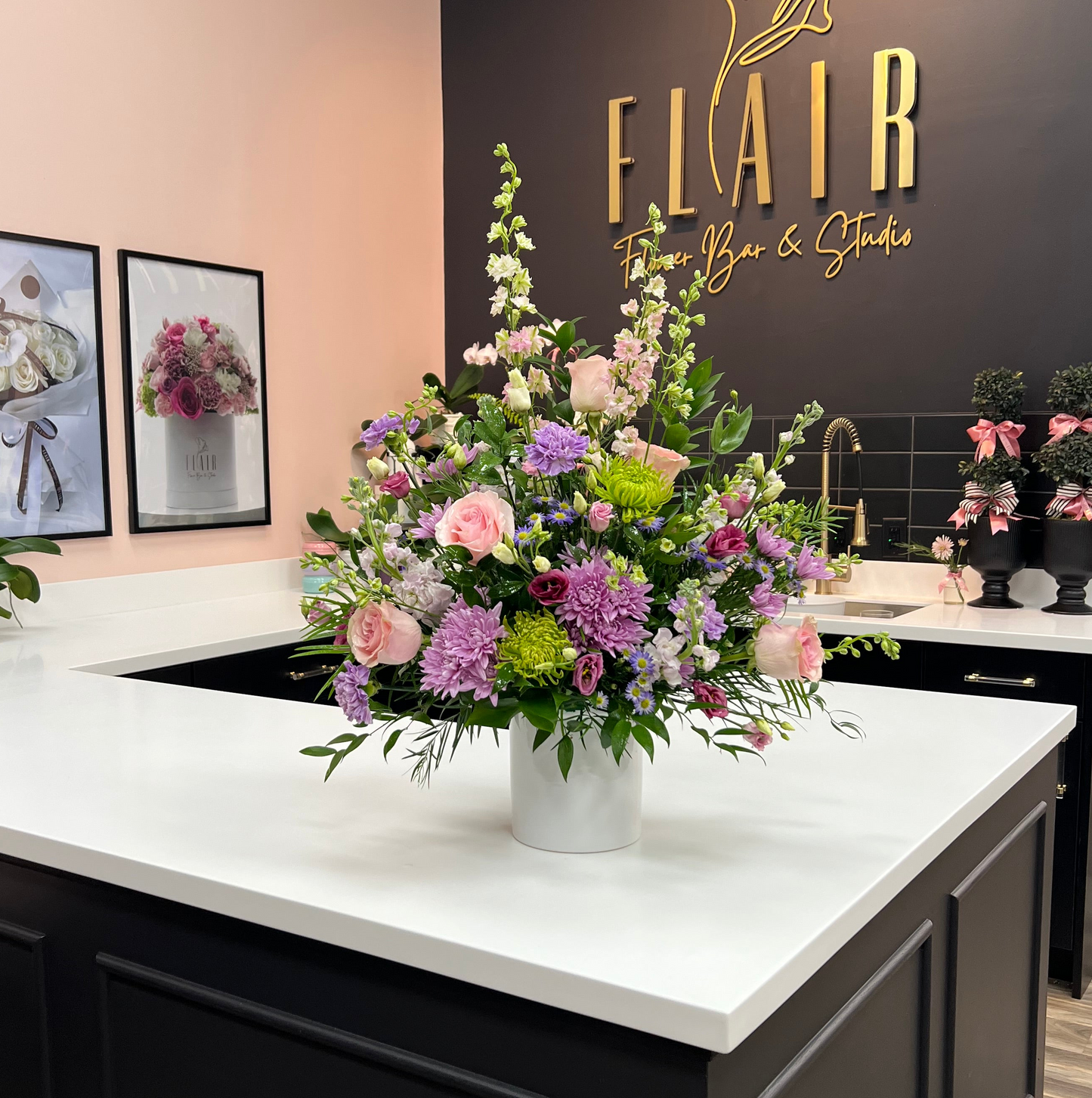 Funeral Floral arrangement on a counter with 'Flair Flower Bar & Studio' sign in the background for local Cincinnati or Northern Kentucky Funeral or Sympathy