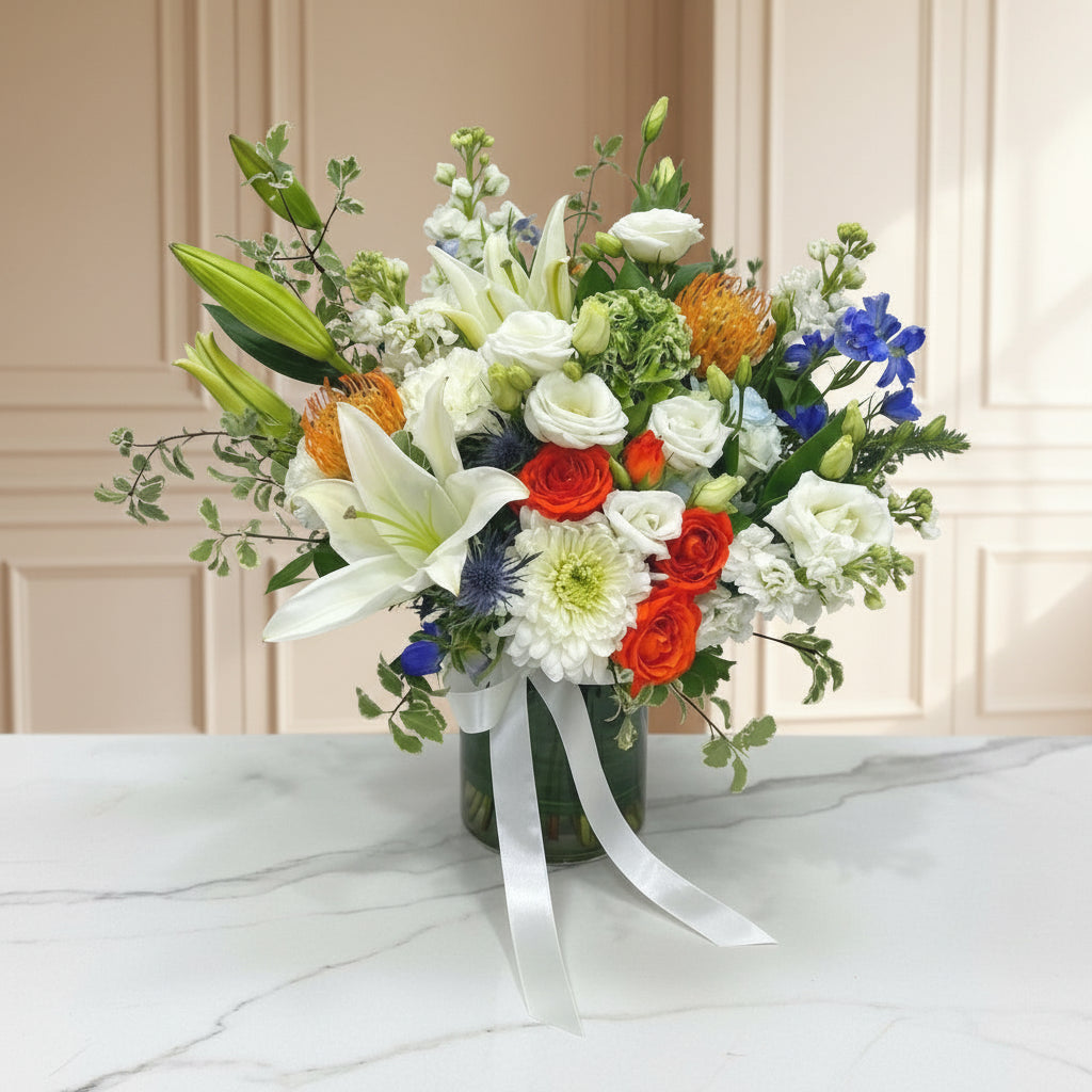 Bouquet of flowers with white, red, and orange flowers on a marble surface.