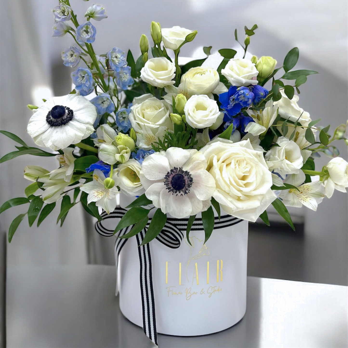 Floral arrangement in a white box with black stripes on a gray background