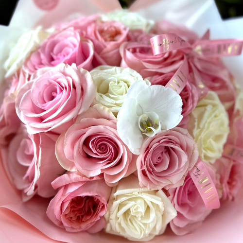 Bouquet of pink and white roses with a white orchid in the center.