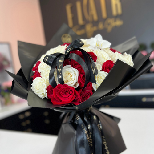 Bouquet of red and white roses with black ribbons in front of a blurred background with Flair Flower Bar branding.