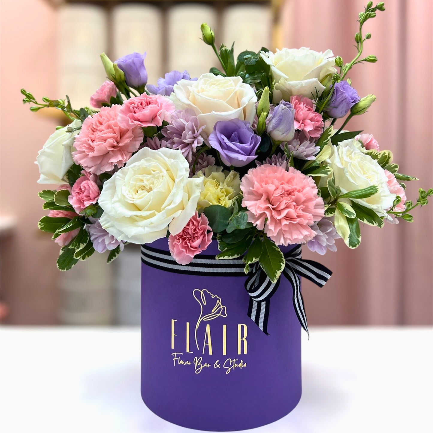Floral arrangement in a purple box with 'Flair' branding on a blurred background