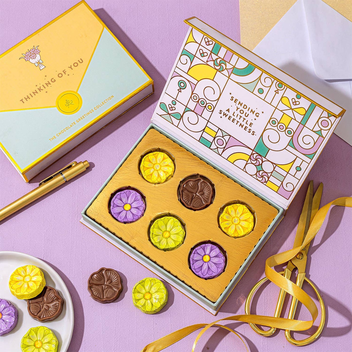 Box of chocolates with decorative lid on a pink background