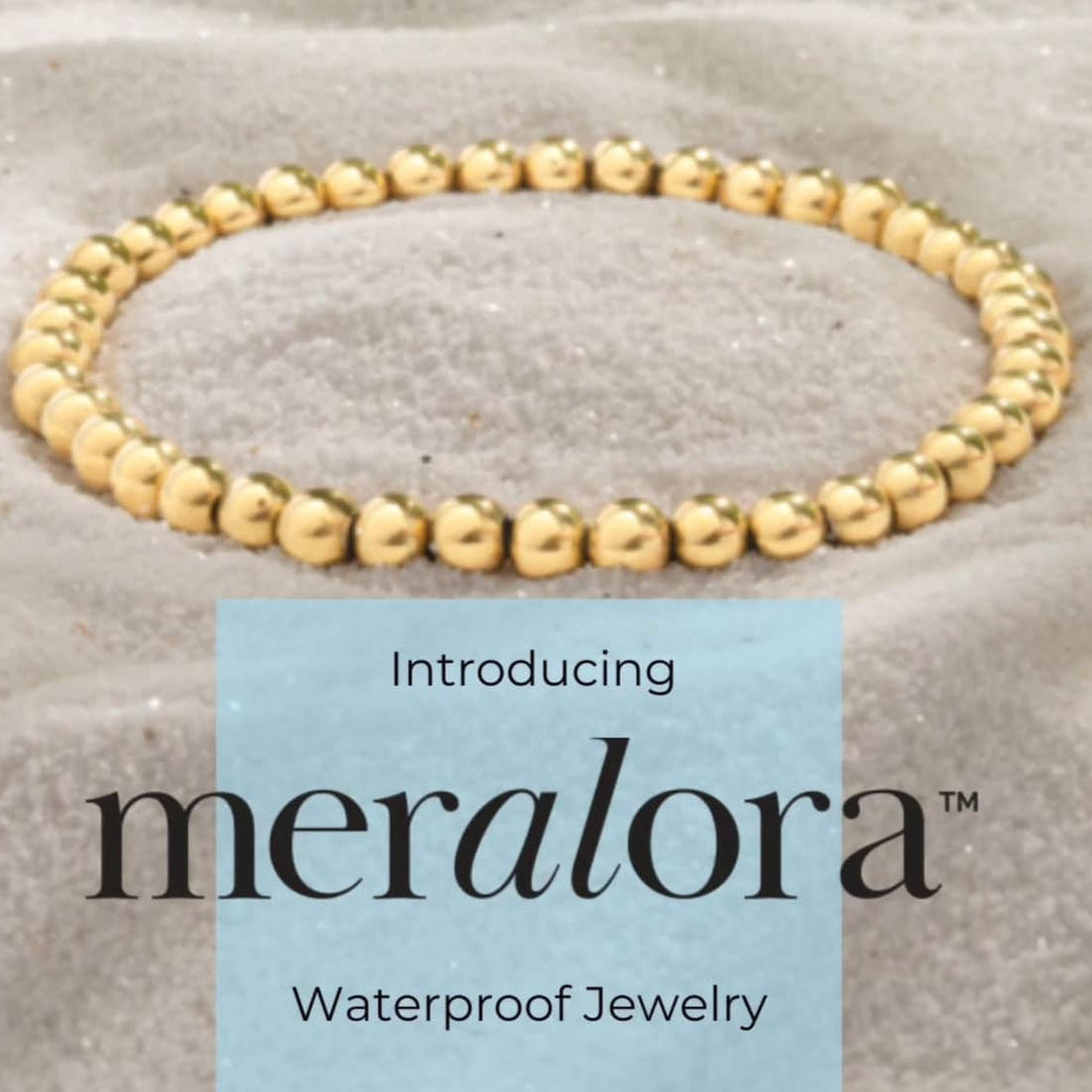 Gold beaded bracelet on a textured surface with 'meralora' branding.