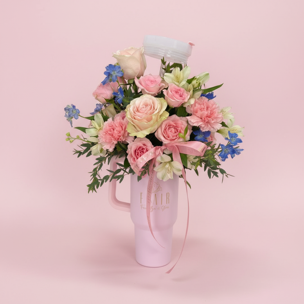 Bouquet of pink and white flowers in a pink mug on a white surface.
