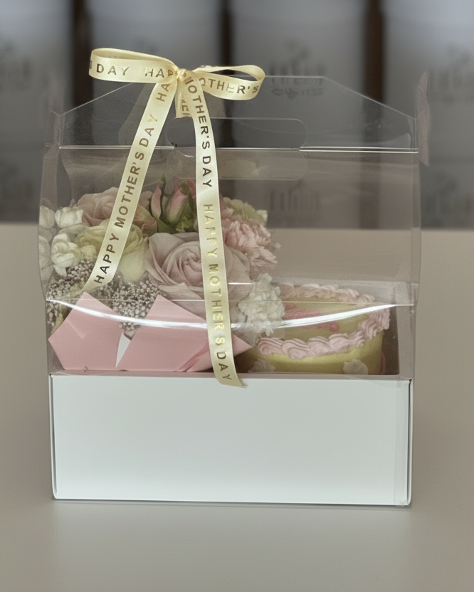 Gift box with flowers and a 'Happy Mother's Day' ribbon on a neutral background Cincinnati Flower & Cake delivery by Flair Flower Bar