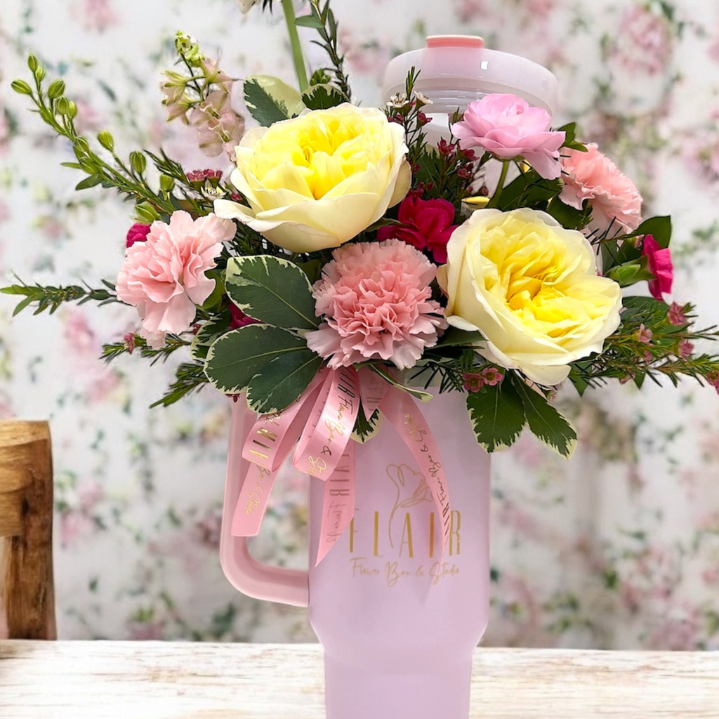 Pink water bottle with flowers and a pink ribbon on a blurred floral background