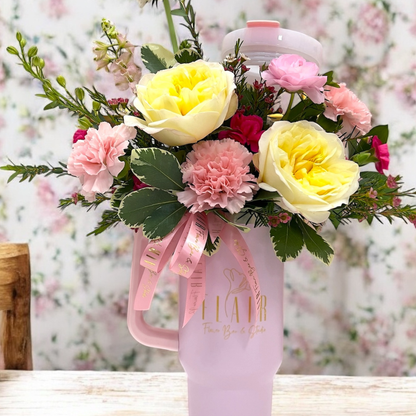 Pink water bottle with flowers and a pink ribbon on a blurred floral background