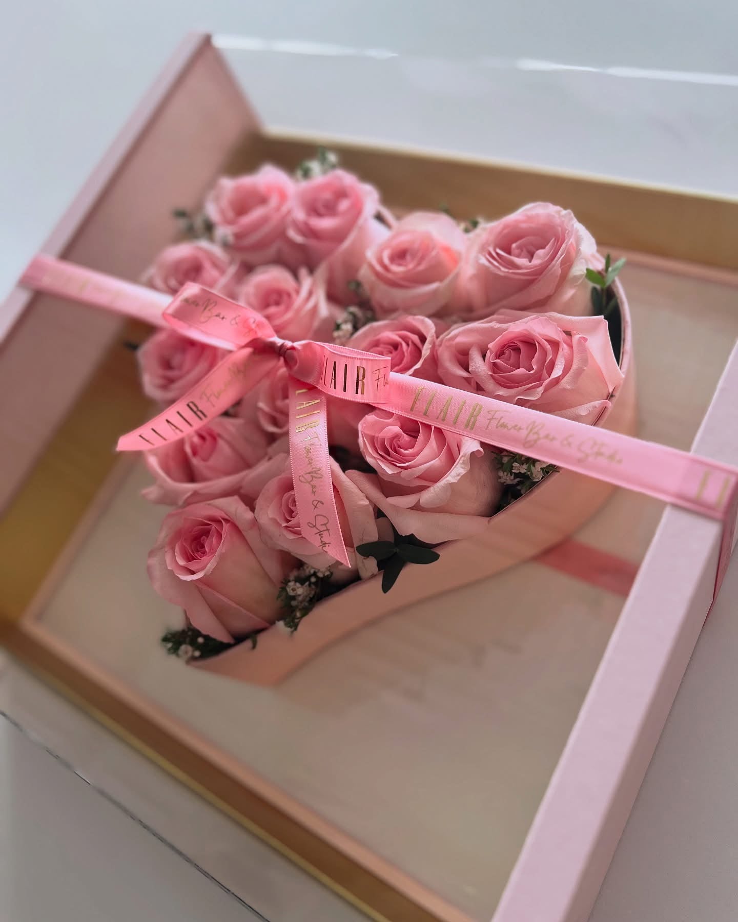 Pink roses in a box with a pink ribbon on a white background