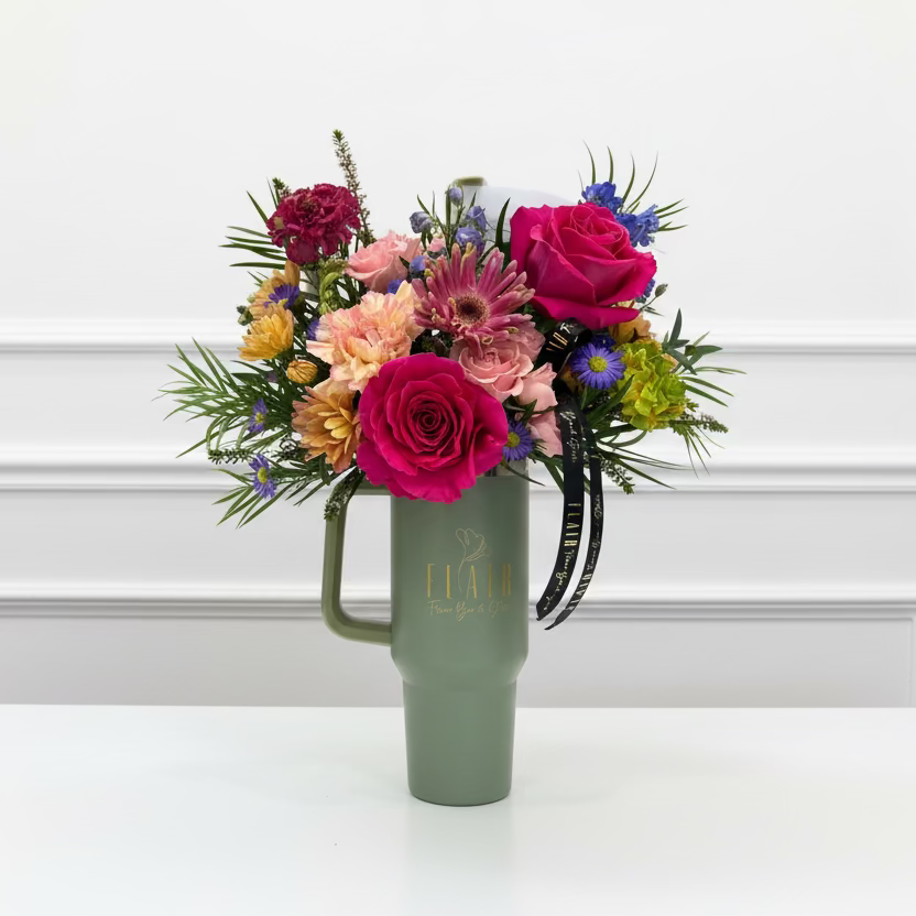 Colorful bouquet in a green tumbler cup with 'Flair' branding against a white wall