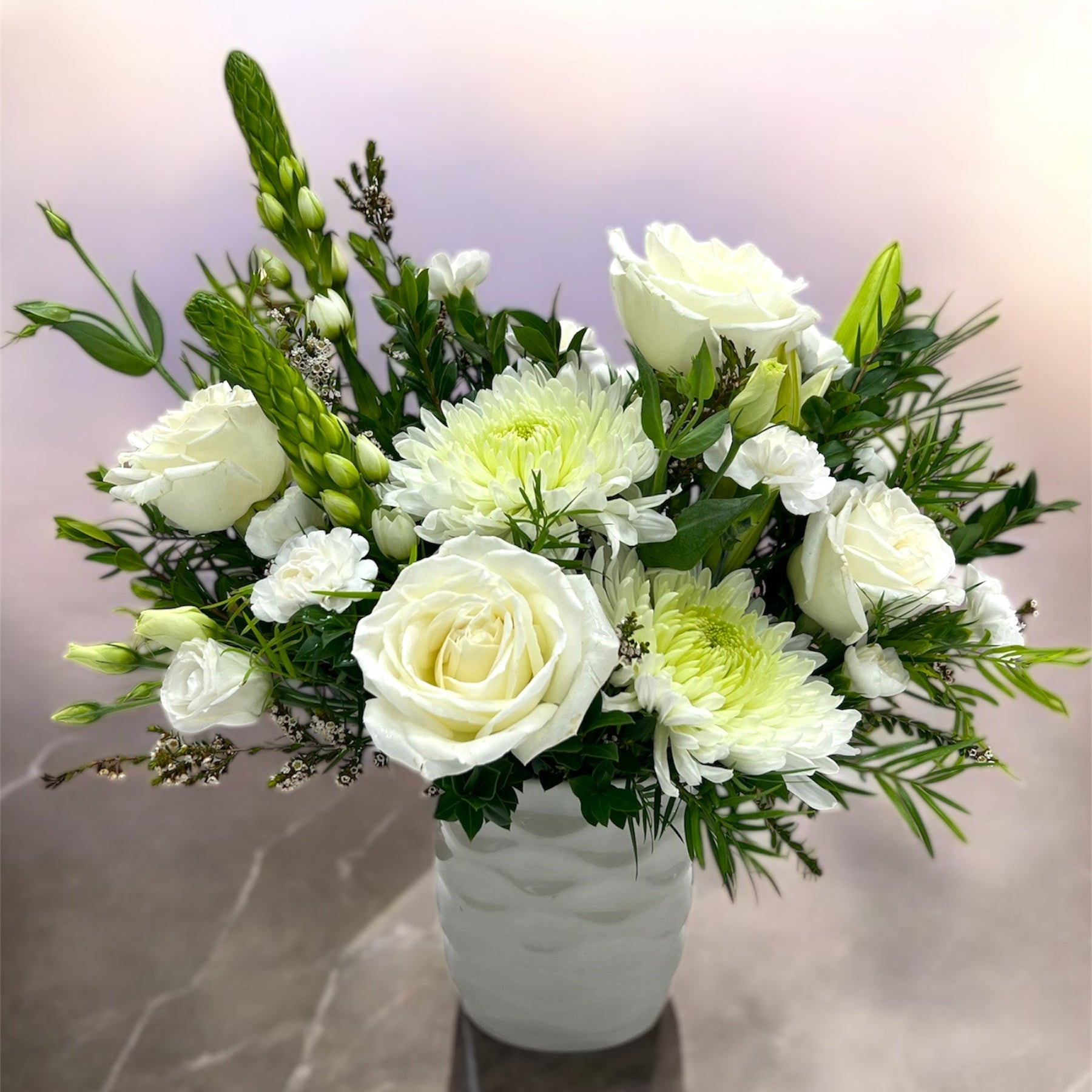 Bouquet of white and green flowers in a white vase on a marble surface