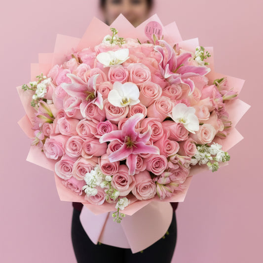 Ramo Buchon Style Rose Bouquet of pink roses with pink lily and orchid accents with a blurred background in Cincinnati