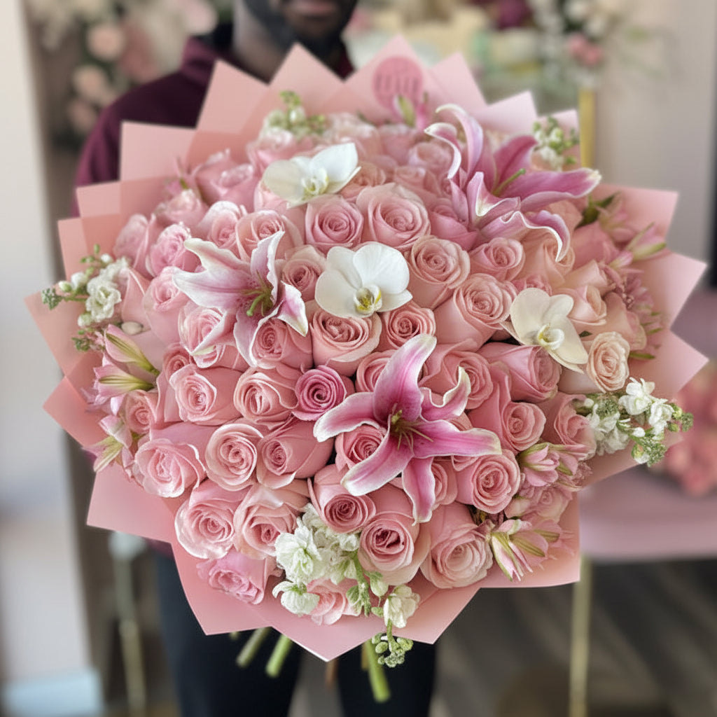 Bouquet of pink roses with white accents of lilies and orchids held by a person for Cincinnati Flower Delivery