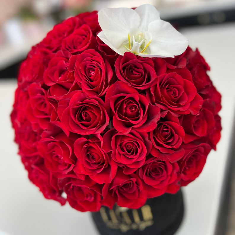 Bouquet of red roses with a white orchid on a blurred background