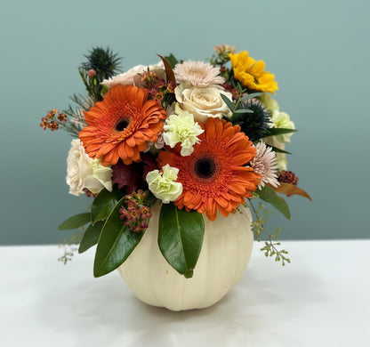 Floral arrangement in a real white pumpkin on a table with a blurred background