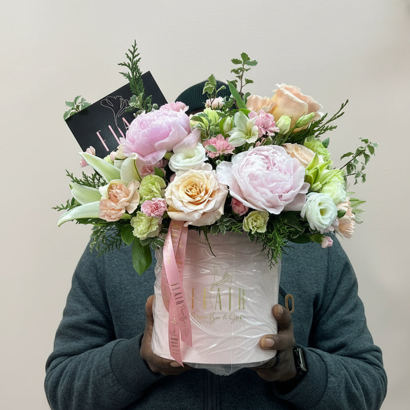 Person holding a bouquet of flowers and a box with Flair on it against a light-colored wall fretting read to go out on delivery to Cincinnati