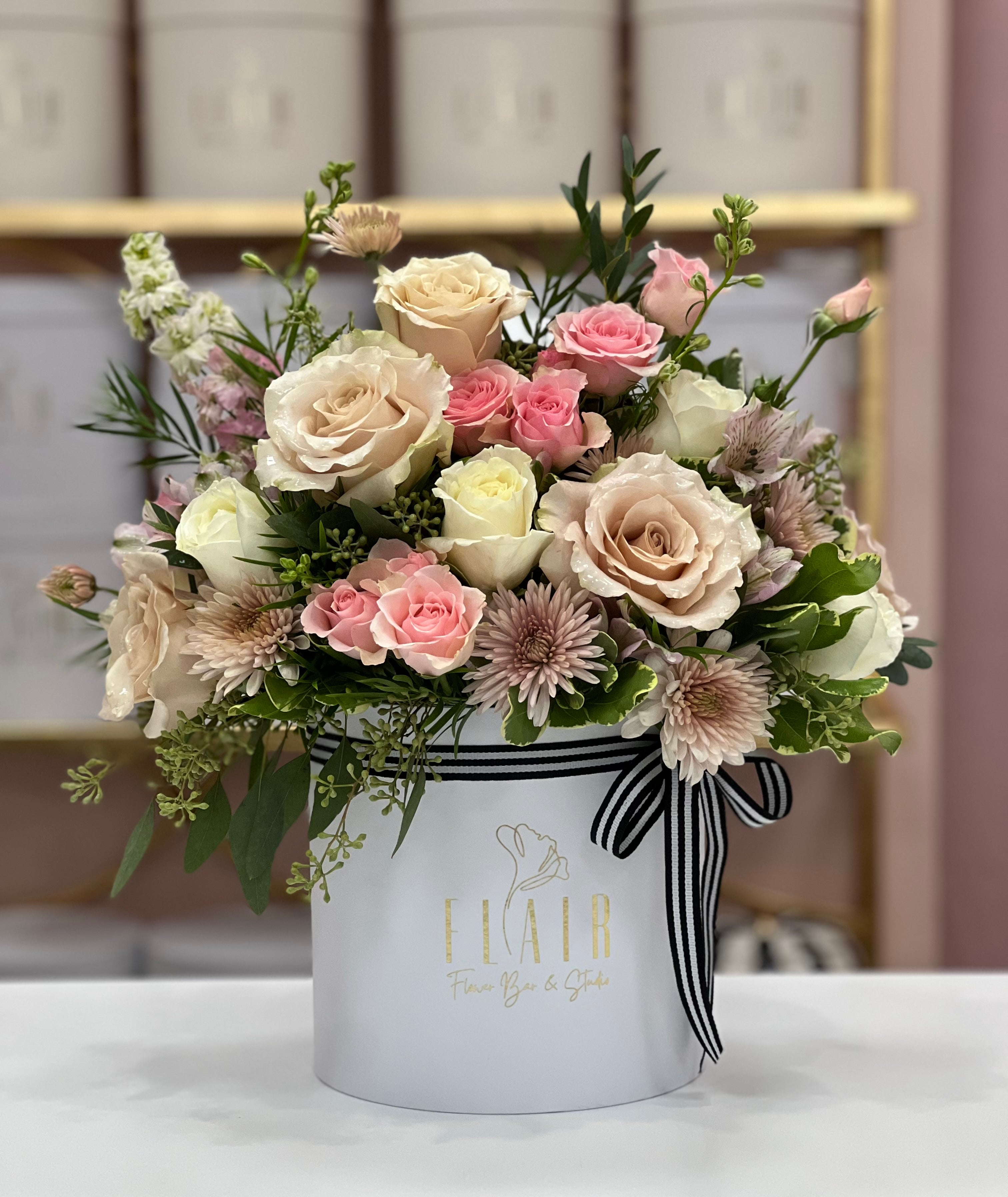 Cincinnati Florist Delivery Floral arrangement in a white box with Flair branding on a marble surface.