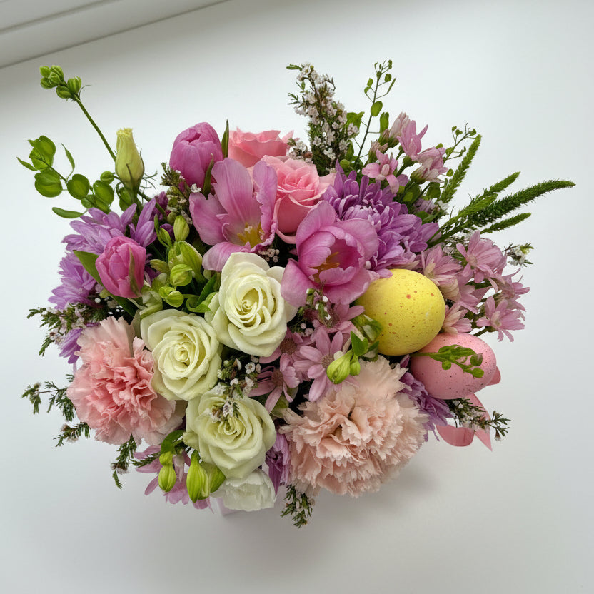Colorful flower arrangement with pink, purple, and green flowers on a white surface.