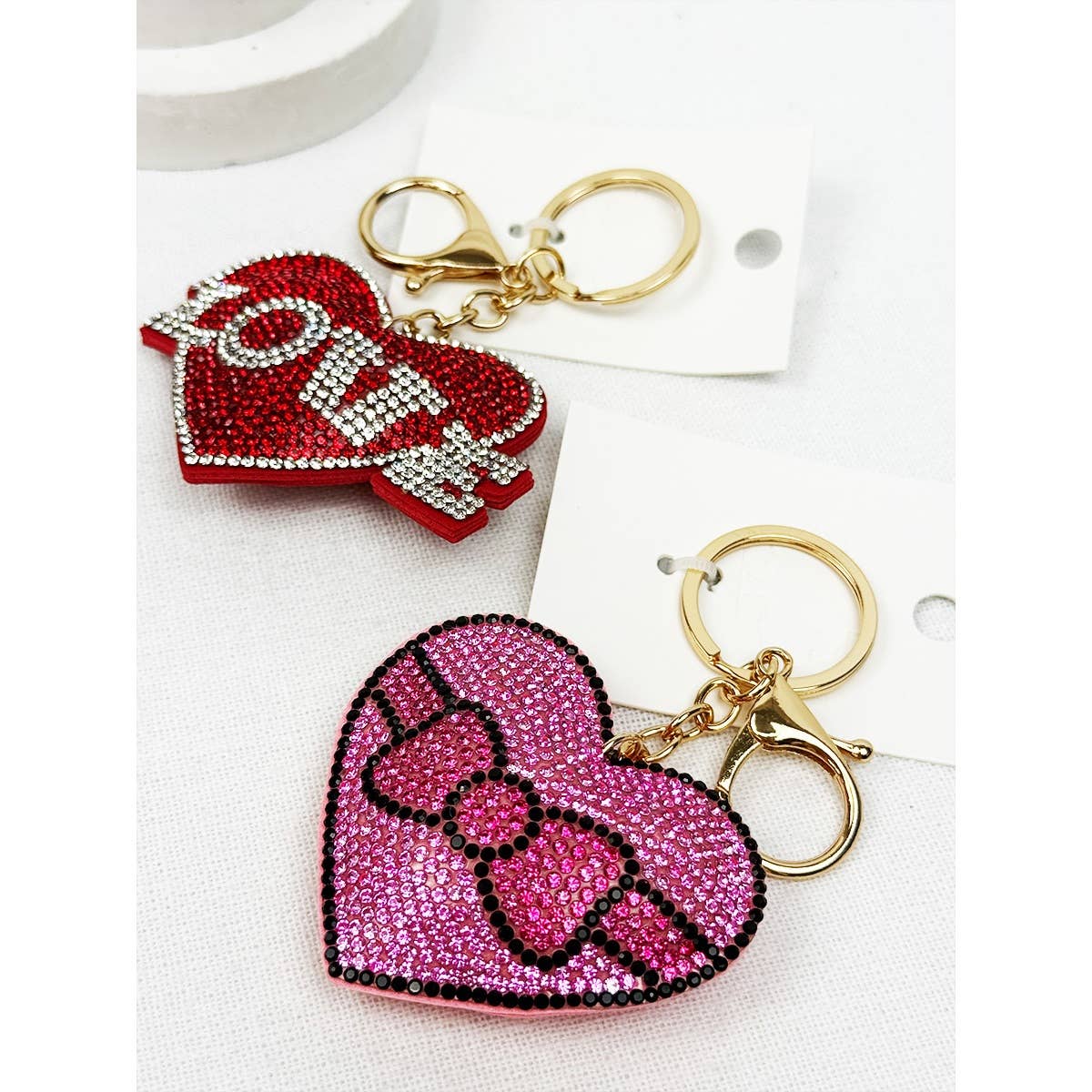 Two heart-shaped keychains with decorative elements on a white background