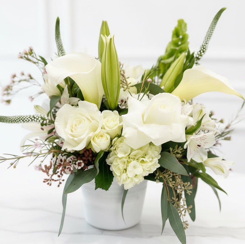 Floral arrangement with white and green flowers on a white surface