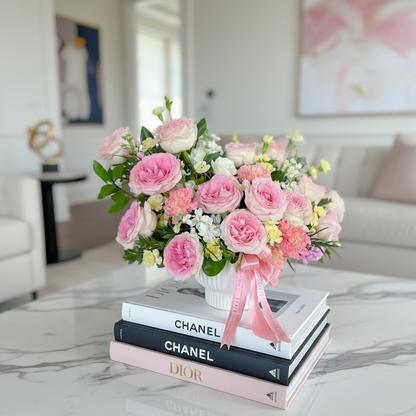 Bouquet of pink flowers with a pink ribbon on Chanel books in a living room setting