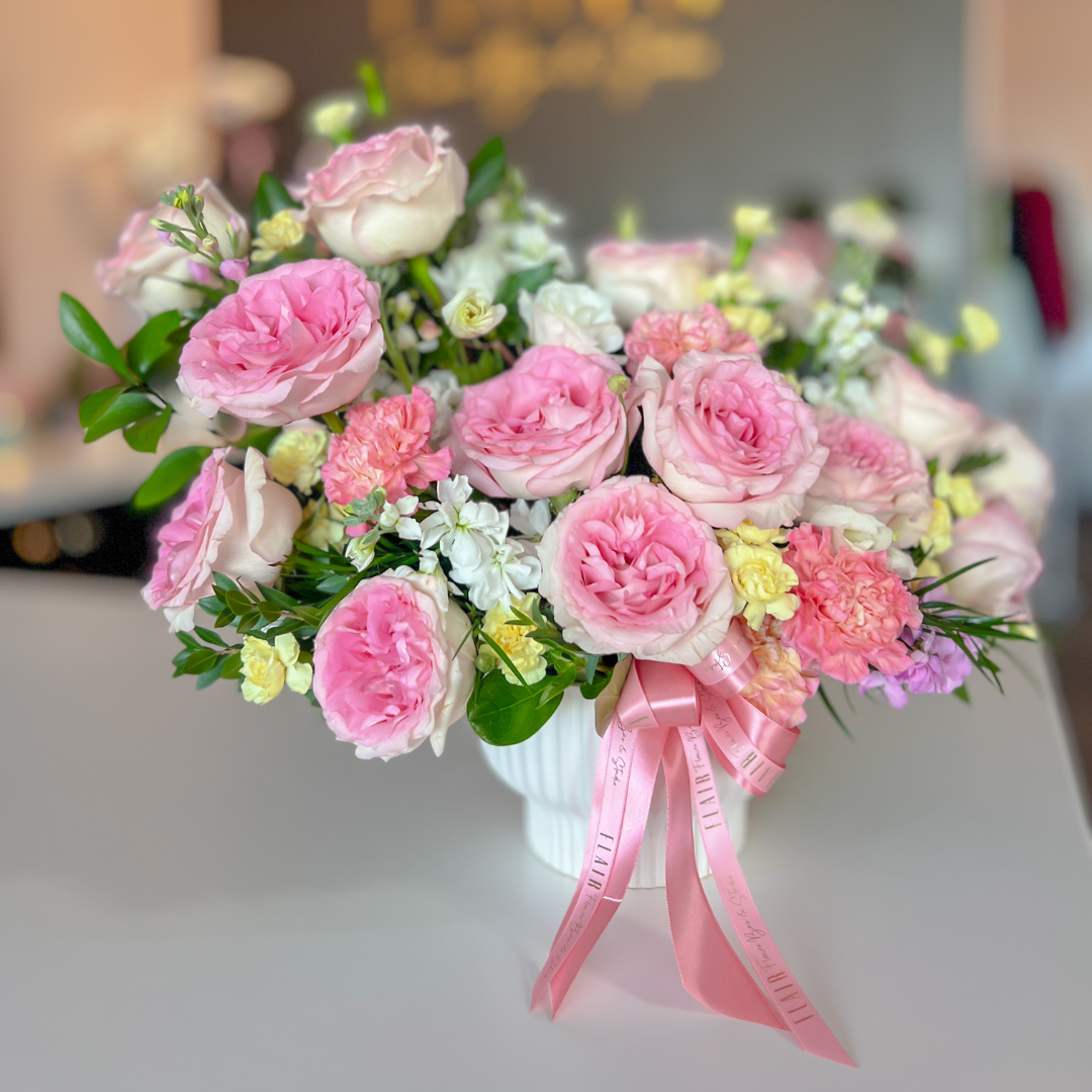 Bouquet of pink and white flowers with a pink ribbon on a blurred background