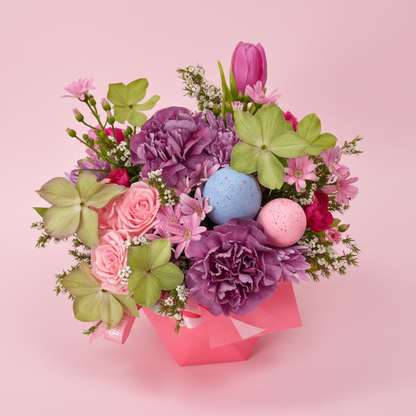Bouquet of flowers with Easter eggs on a pink background