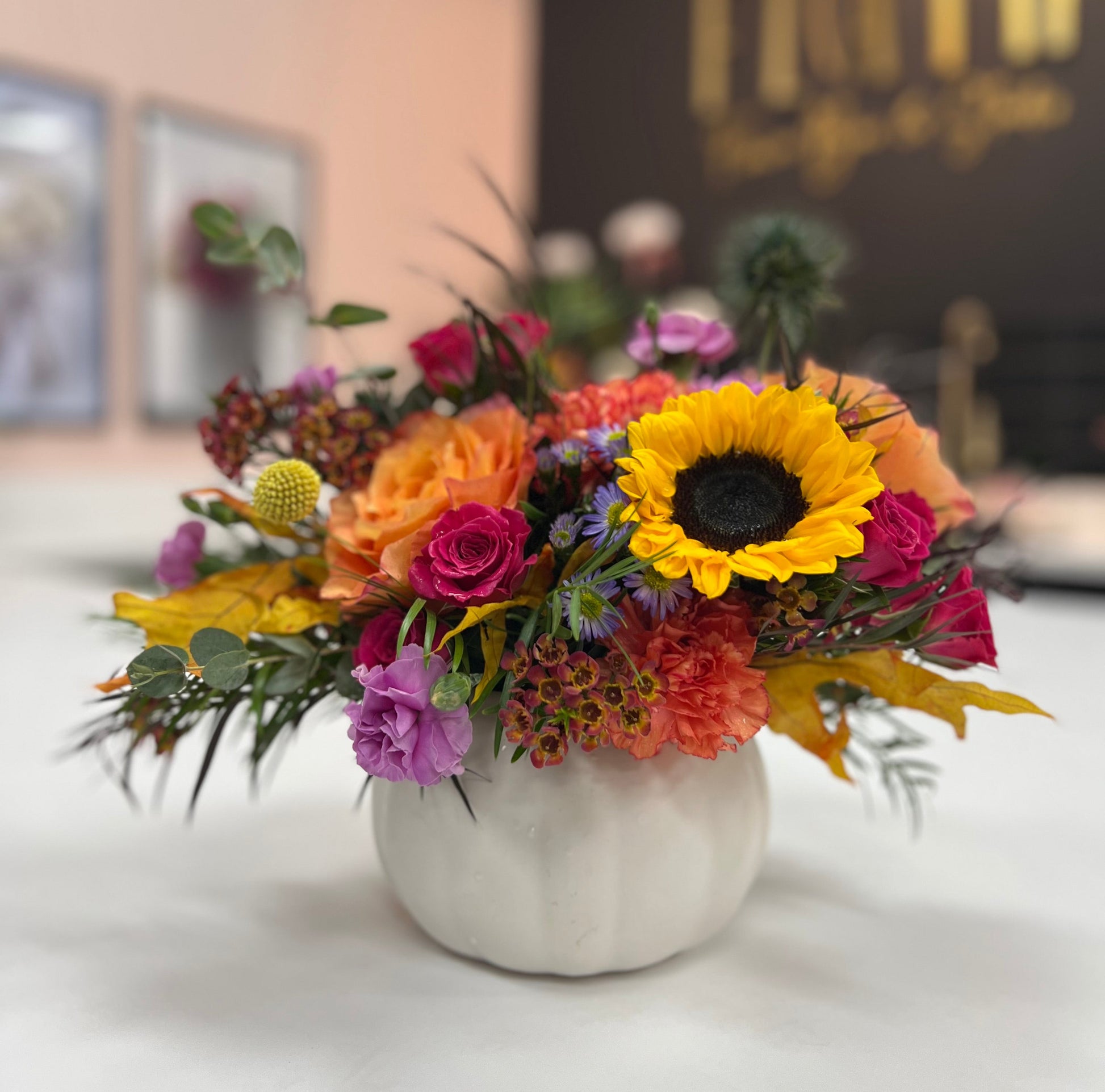 Colorful flower arrangement in a white vase on a table with a blurred background