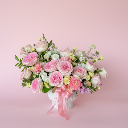 Bouquet of pink and white flowers with a pink ribbon on a pink background