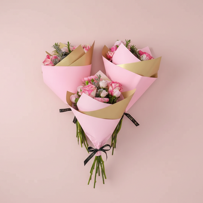 Three flower bouquets wrapped in pink and gold paper against a pink background.