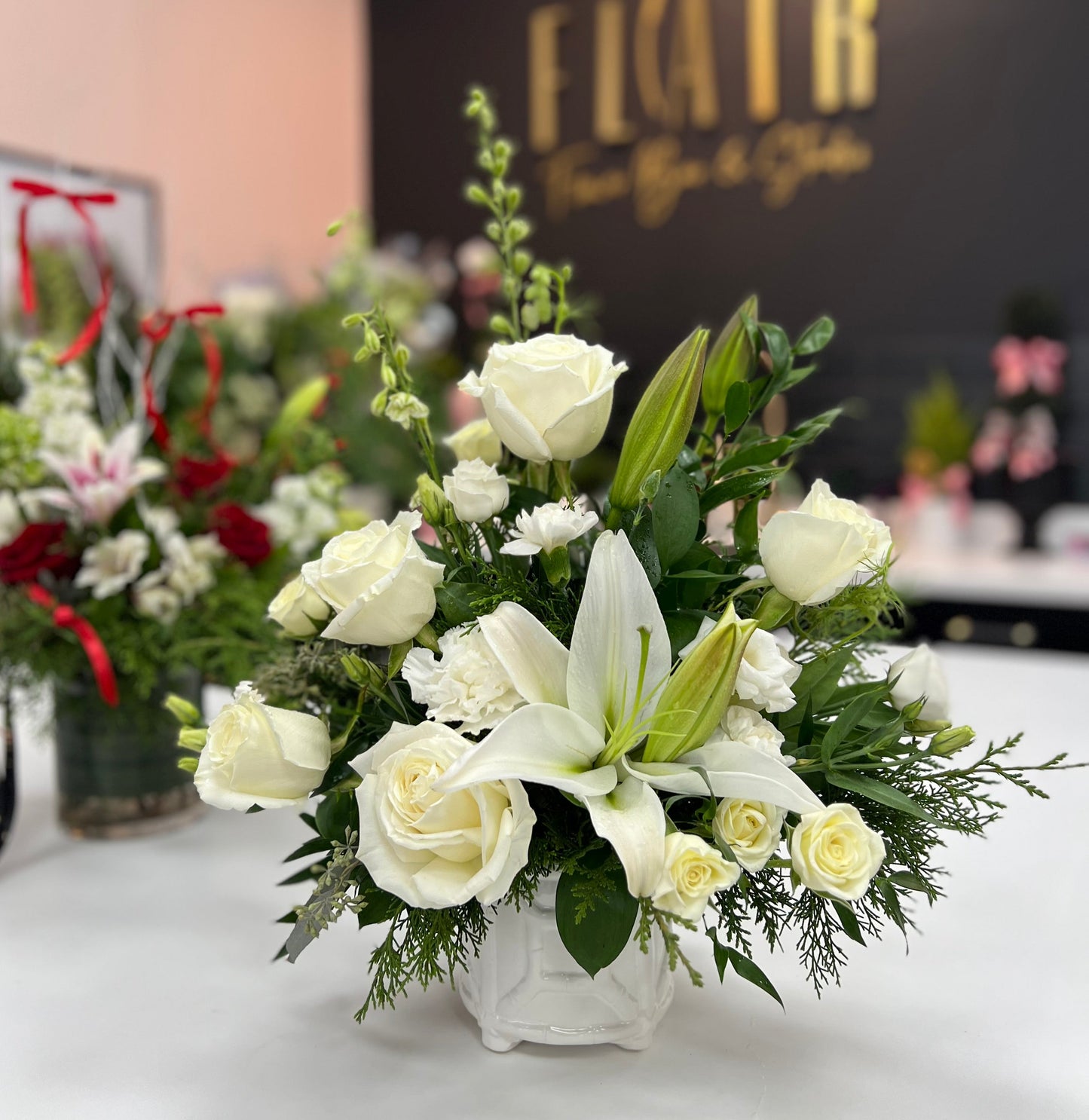 Floral arrangement in a white vase on a table with 'Flair' branding in the background.