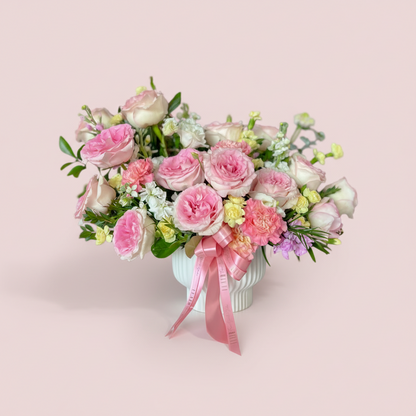 Bouquet of pink and white flowers with a pink ribbon in a pink background