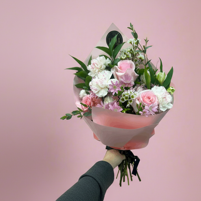 Bouquet of flowers wrapped in pink paper against a pink background