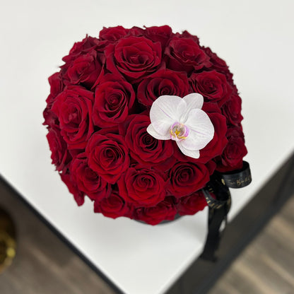 Bouquet of red roses with a white orchid on a white surface in Florence, Kentucky flower shop, Flair Flower Bar