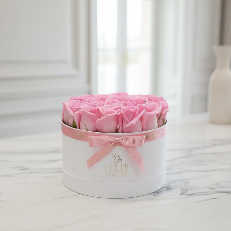Heart-shaped box of pink roses with a bow on a white surface Flair Flower Bar in Florence 