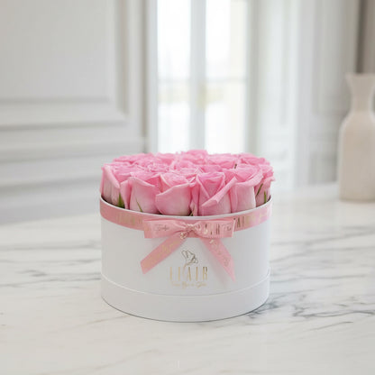 Heart-shaped box of pink roses with a bow on a white surface Flair Flower Bar in Florence 
