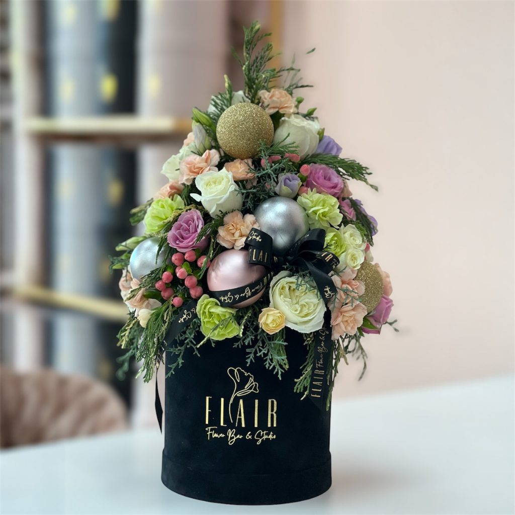 Decorative flower arrangement in a black box with 'Elair' branding on a blurred background