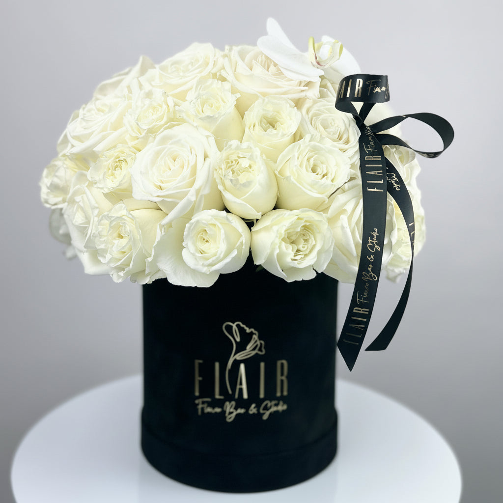 Black box with white roses and a black ribbon on a gray background by Flair Flower bar | Cincinnati 