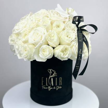 Black box with white roses and a black ribbon on a gray background by Flair Flower bar | Cincinnati 