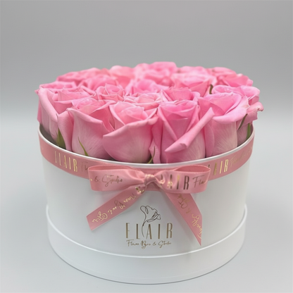 Round white box with pink roses and a pink bow, branded 'Flair'.