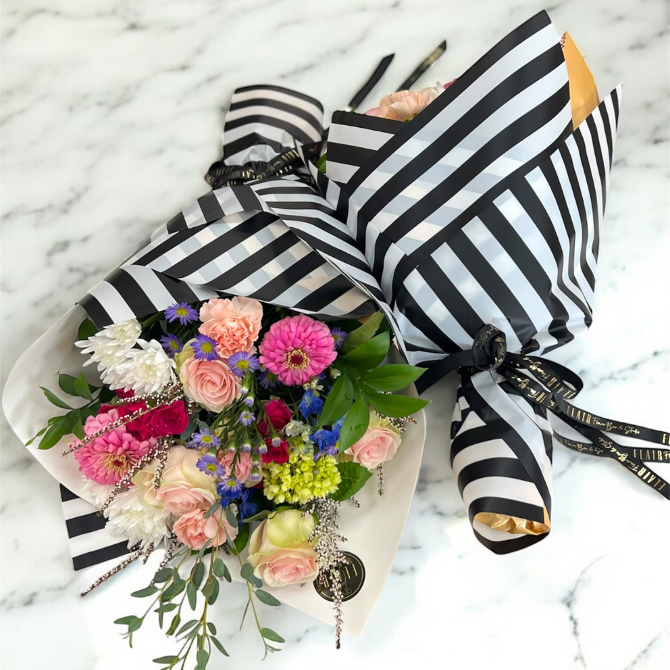 Bouquet of flowers wrapped in black and white striped paper on a marble surface