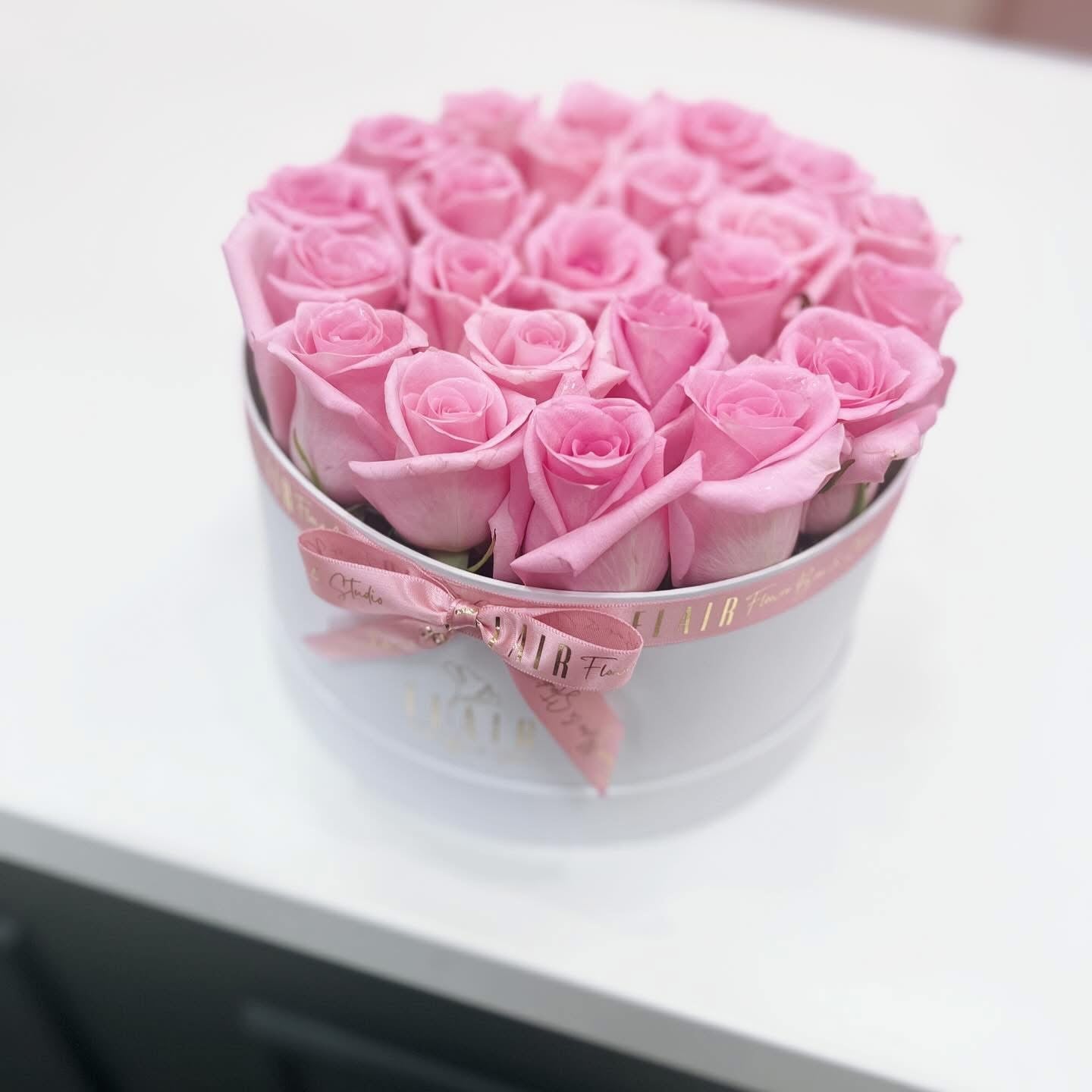 Heart-shaped box of pink roses on a white surface
