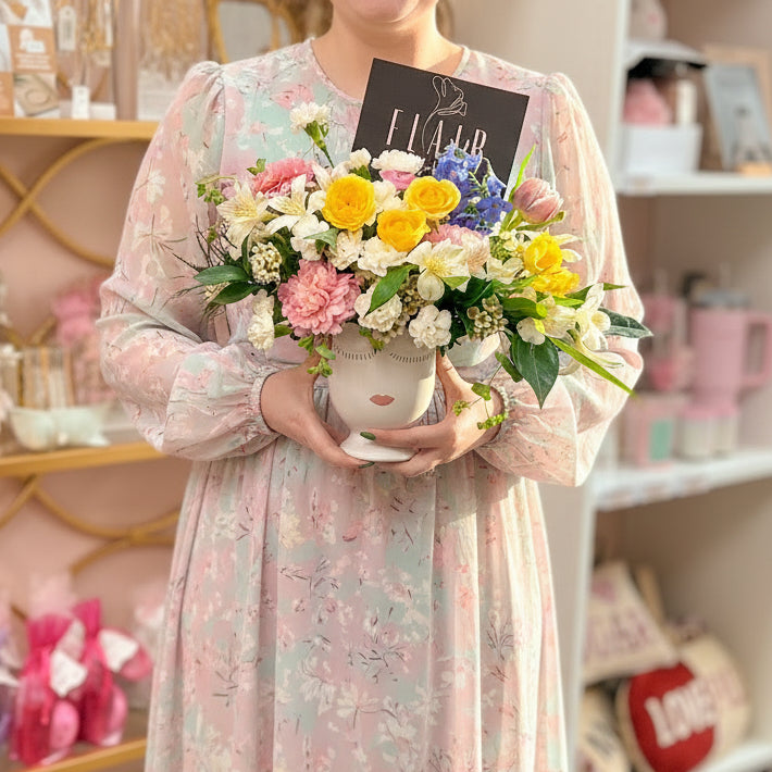 Person holding a colorful bouquet of flowers in a store setting