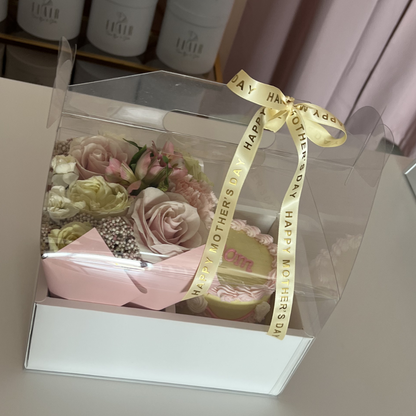 Clear box with a bouquet of flowers and a yellow ribbon on a light pink Flair boxes in background