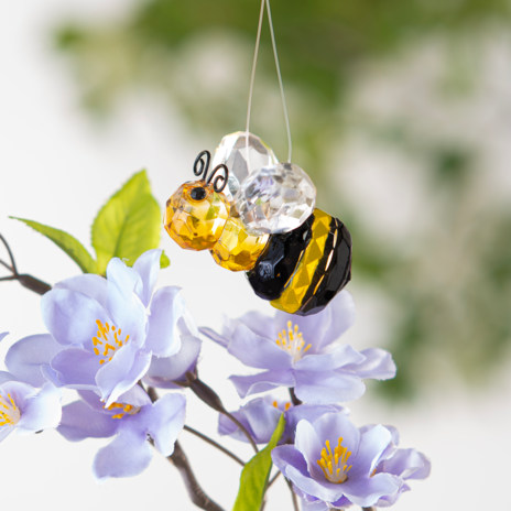 Decorative bee ornament with a clear crystal on a blurred floral background