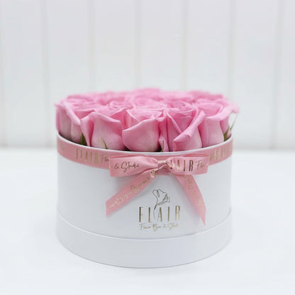 Pink roses in a white box with a pink bow, branded 'Flair Flower Bar  & Gifts'.