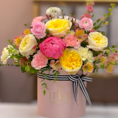 Bouquet of flowers in a pink box with a black and white ribbon on a blurred background