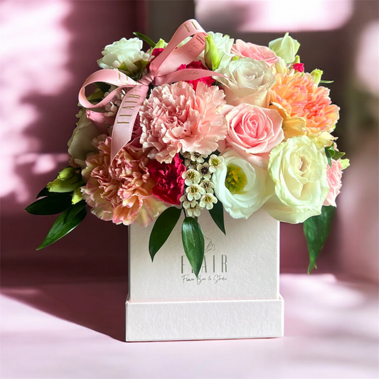 Floral arrangement in a box with a pink ribbon on a blurred background