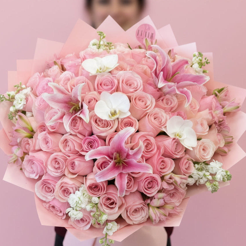 Ramo Buchon Style Rose Bouquet of pink roses with pink lily and orchid accents with a blurred background in Cincinnati